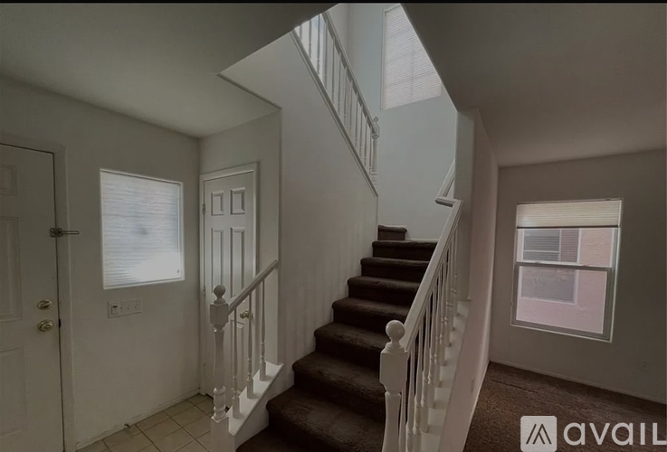 A staircase with a carpeted runner and white balusters leads up to a window.