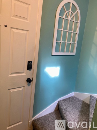 A white door with a black handle and a window on the wall.