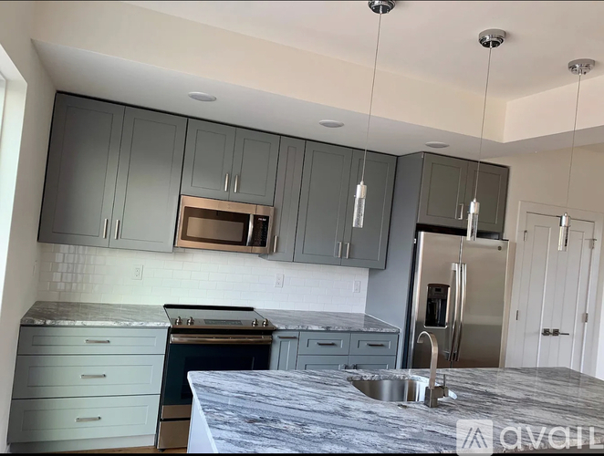 A kitchen with a stainless steel refrigerator and grey cabinets.