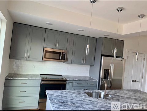 A kitchen with a stainless steel refrigerator and grey cabinets.