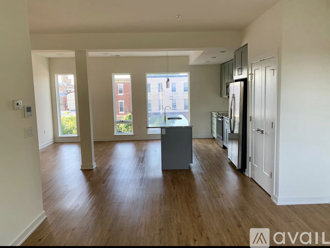 A spacious kitchen with wooden floors and white walls.