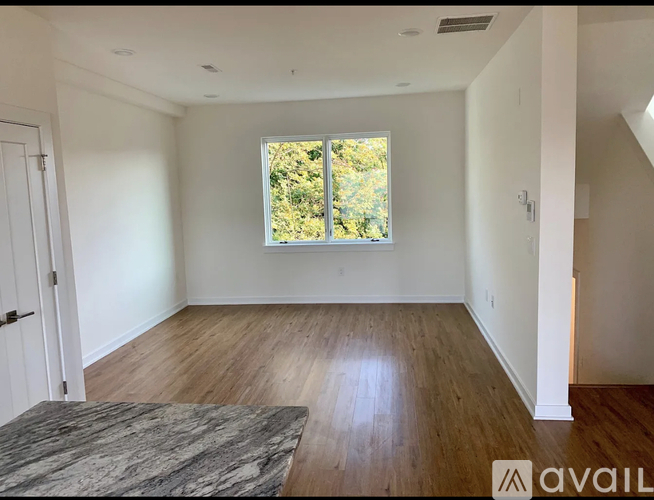 A spacious room with wooden floors and a large window.