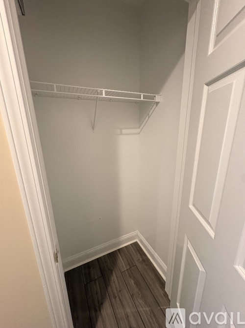 Empty white closet with a white door and a white shelf.
