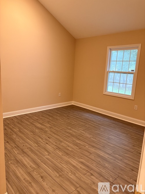 A room with wooden flooring and a window.