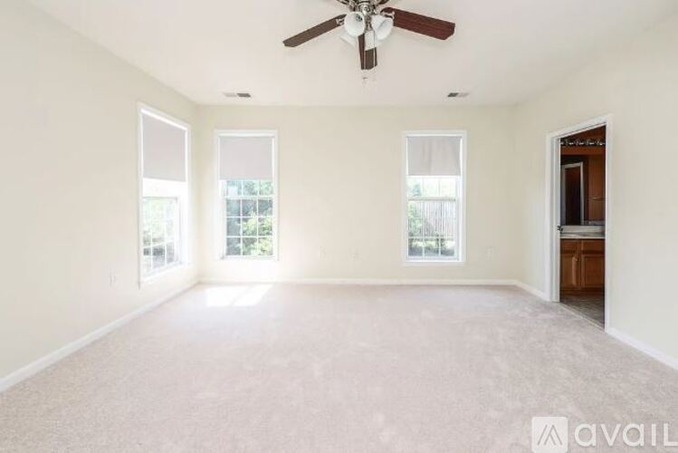 A spacious room with a ceiling fan and carpeted floor.