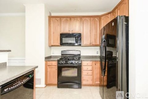 A kitchen with wooden cabinets and black appliances.