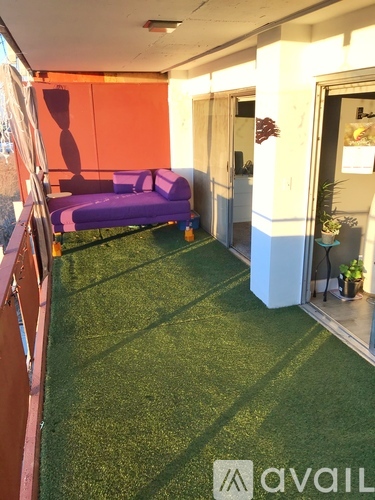 A room with a purple couch and artificial grass.