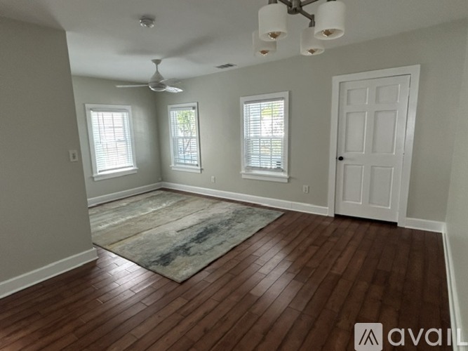 A room with wooden floors and a rug in the middle.