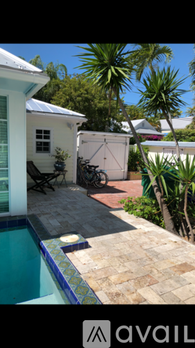 A pool with a tiled edge and a patio area with a table and chairs.