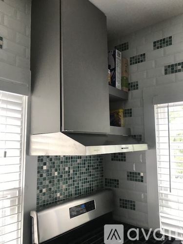 A kitchen with a stainless steel range hood and a tiled backsplash.
