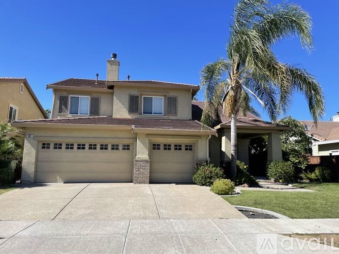 A two-story house with a garage and a palm tree in front.