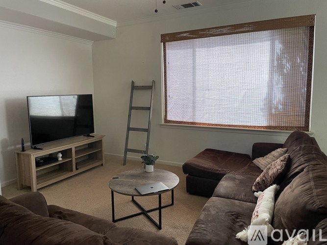 A living room with a brown couch, a coffee table, and a television.