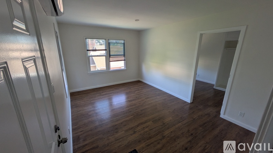 A room with wooden floors and a window with a view of a building outside.