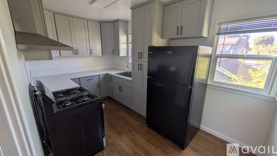 A kitchen with black appliances and wooden floors.