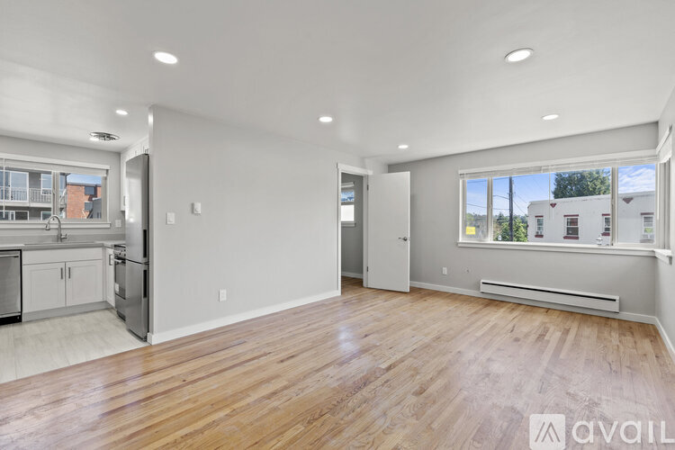 A spacious living room with wooden flooring and a large window overlooking a residential area.
