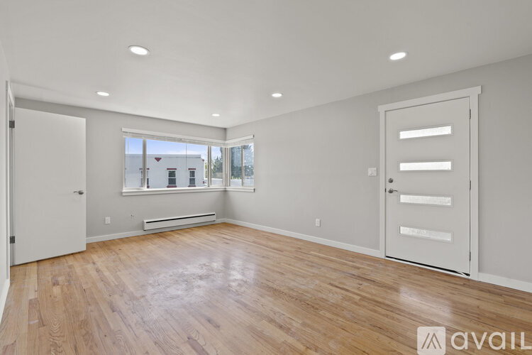 A spacious room with wooden floors and white walls.