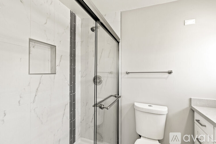 A white toilet sits next to a walk-in shower with a glass door.