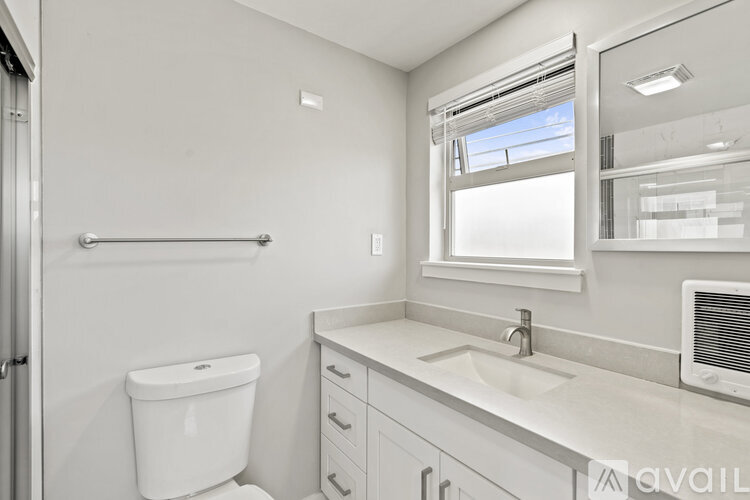 A white bathroom with a toilet, sink, and mirror.