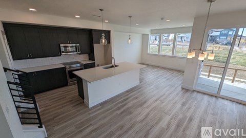 A modern kitchen with black cabinets and a wooden floor.
