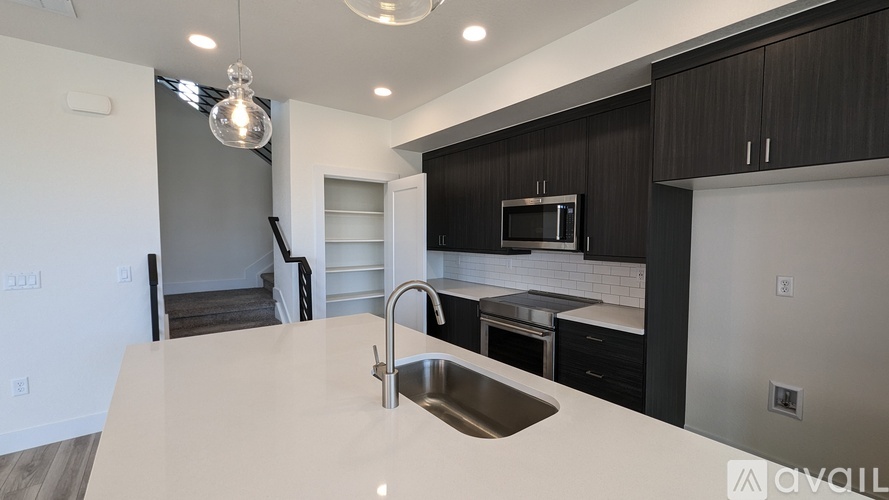 A modern kitchen with a white countertop and dark cabinets.