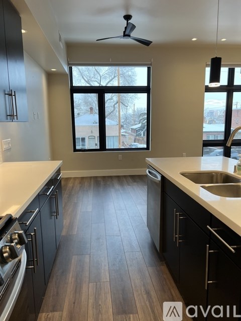 A kitchen with black cabinets and a wooden floor.