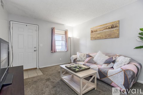 A living room with a couch, a coffee table, and a painting on the wall.