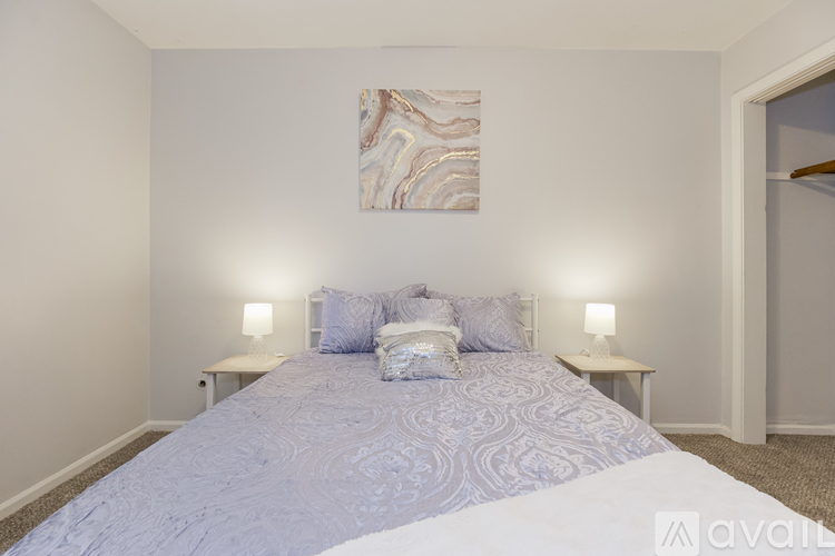 A bedroom with a large bed and two lamps.