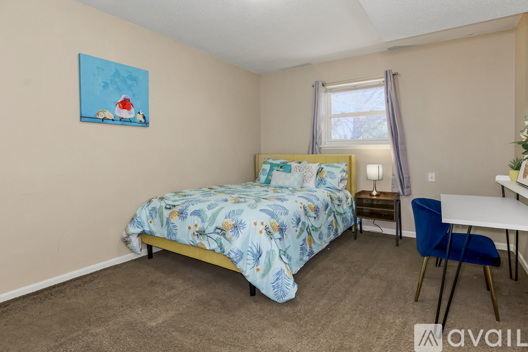 A bedroom with a bed, chair, and a painting on the wall.