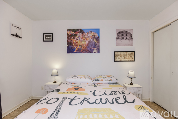 A bedroom with a bedspread that says "Time to travel" and pictures of famous landmarks on the wall.