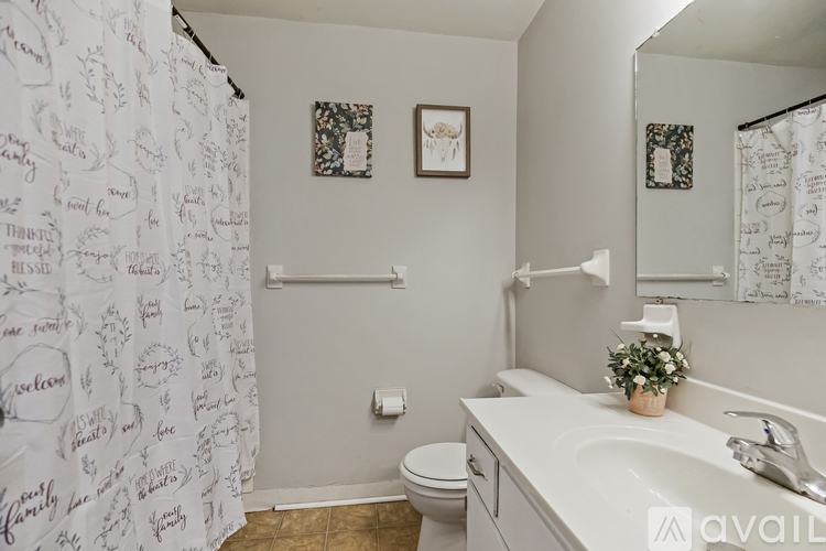 A bathroom with a toilet, sink, and shower curtain with writing on it.
