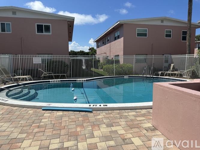 A pool surrounded by a fence and two houses.