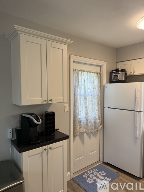A kitchen with white cabinets and a black refrigerator.