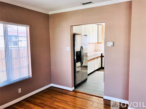 A kitchen with a refrigerator and a view of a building outside the window.