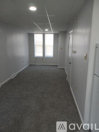 A long, empty hallway with carpeted floors and white walls.