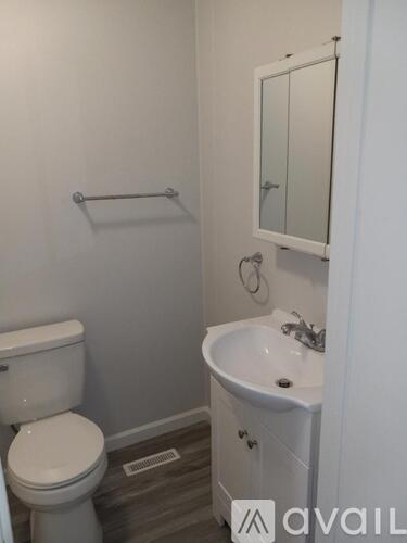A white toilet sits next to a white sink in a small bathroom.