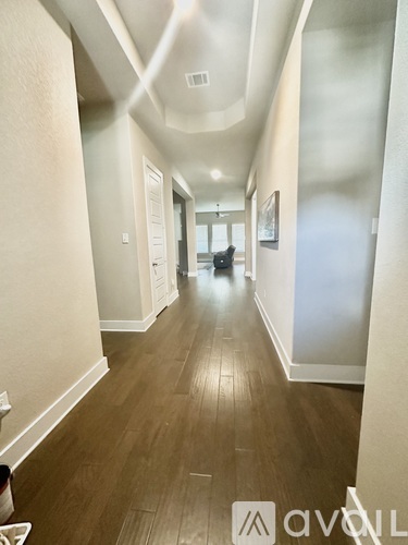 A long hallway with wood floors and white walls.
