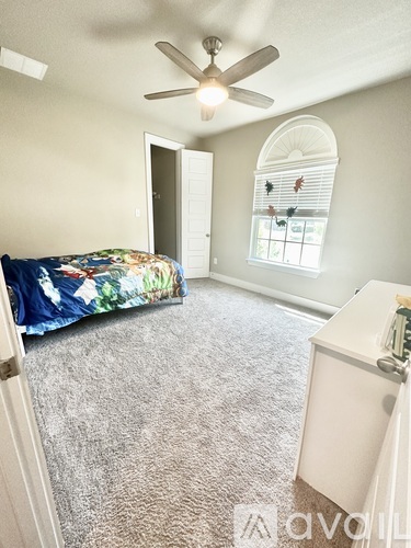 A bedroom with a bed, a window with blinds, and a ceiling fan.