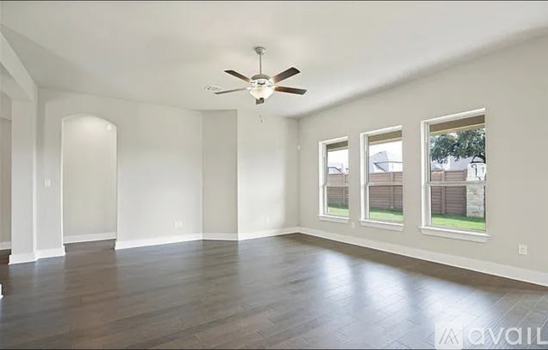 A spacious room with a ceiling fan and hardwood flooring.