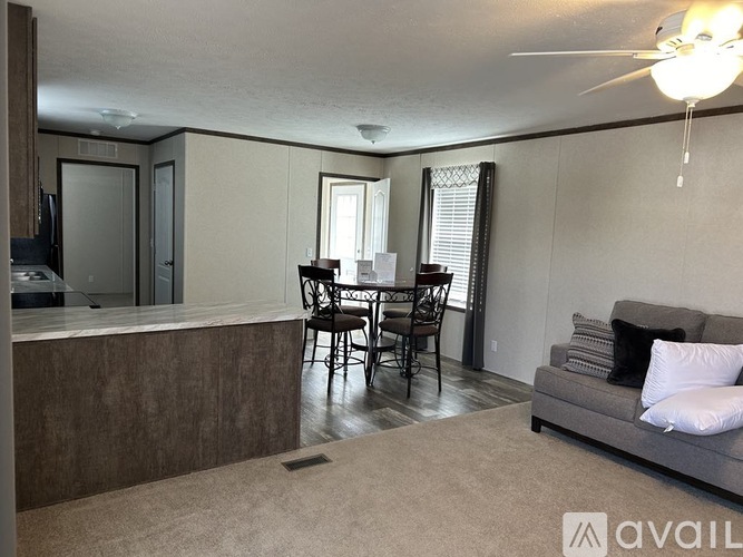 A living room with a grey couch and a dining table with chairs.