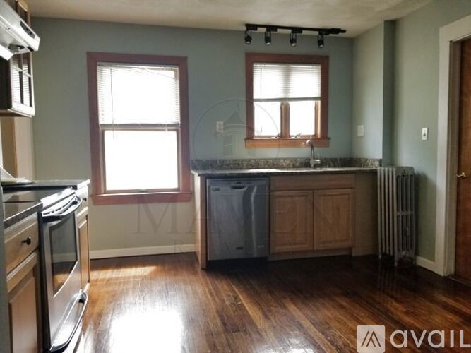 A kitchen with wooden floors and a stainless steel dishwasher.