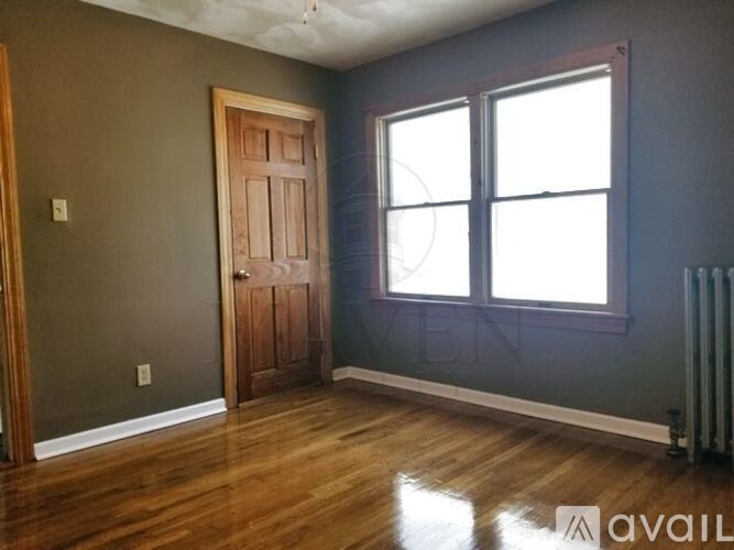 A room with a wooden door and a window with white curtains.