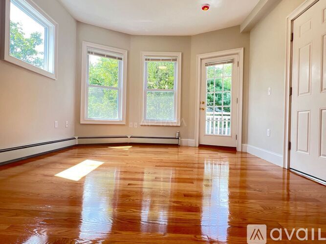 A room with wooden floors and three windows.