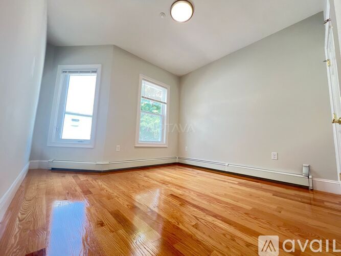 A room with wooden floors and two windows.