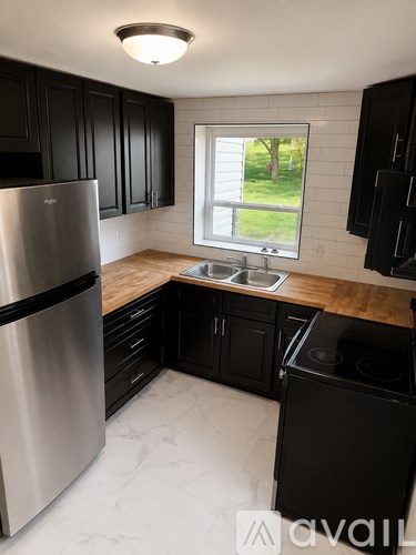 A kitchen with black cabinets and a stainless steel refrigerator.