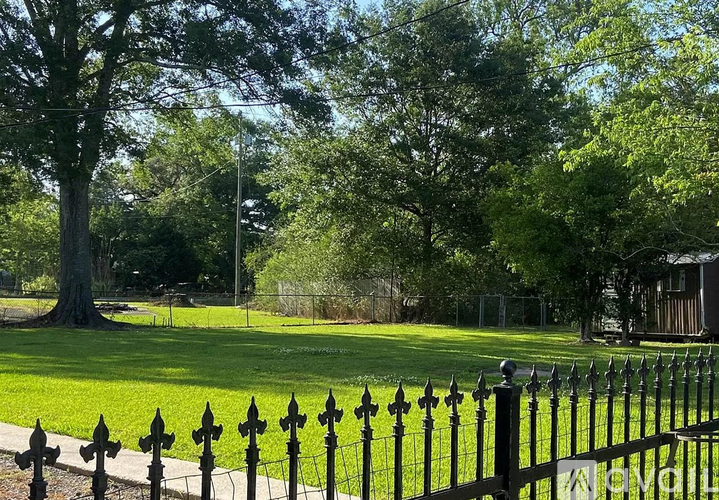 A black fence in front of a green field.