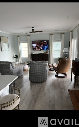 A living room with a grey sofa, a brown armchair, and a television on the wall.