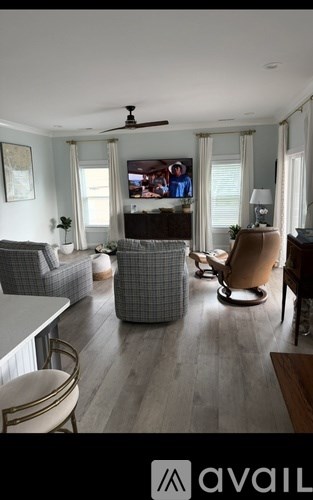 A living room with a grey sofa, a brown armchair, and a television on the wall.