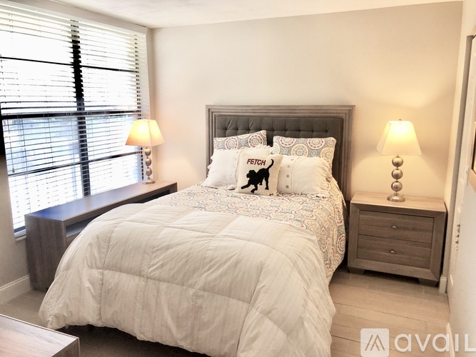 A bedroom with a large bed and two lamps.