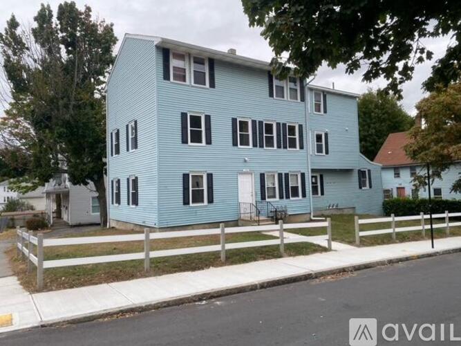 A blue two-story house with a white fence in front.