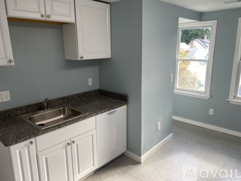 A kitchen with white cabinets and a granite countertop.